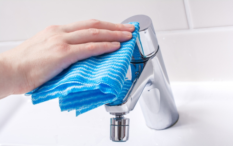 wiping a faucet dry to prevent hard water stains